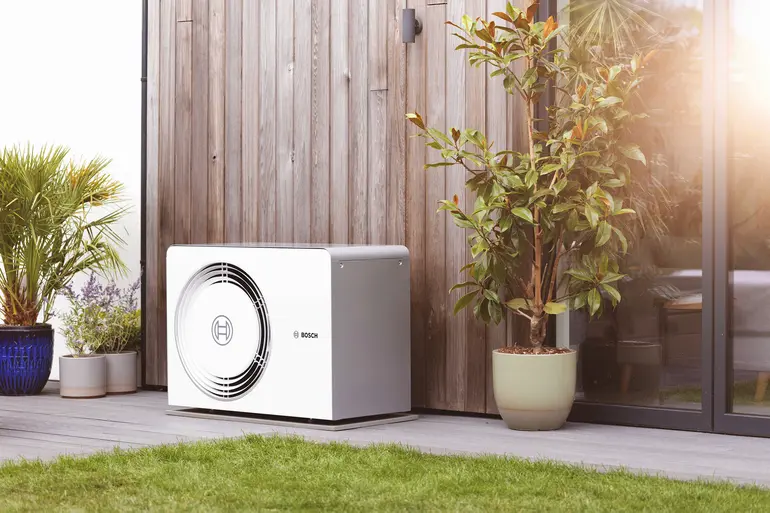Bosch Wärmepumpe an einer Hausfassade mit Terrasse und Pflanzen